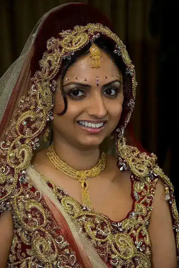Bride in ornate red and gold wedding outfit with bridal veil